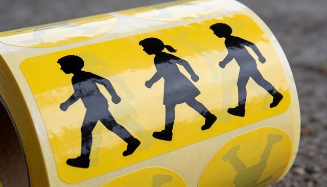 Yellow pedestrian sticker strip featuring three child silhouettes walking