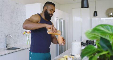 Man Pouring Smoothie in Modern Kitchen with Marble Island
