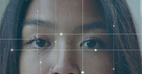 Gazing chinese woman wearing hoop nose ring with futuristic augmented reality grid overlay