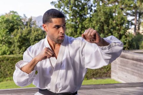 Man practicing martial arts outdoors in white gi on wooden deck