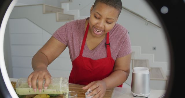 Happy african american plus size woman wearing apron, making cooking vlog with camera in kitchen. healthy lifestyle, enjoying leisure time at home.