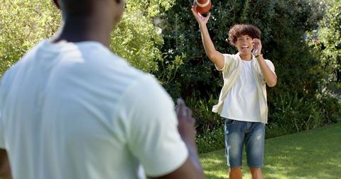 Friends Throwing American Football in Sunlit Backyard