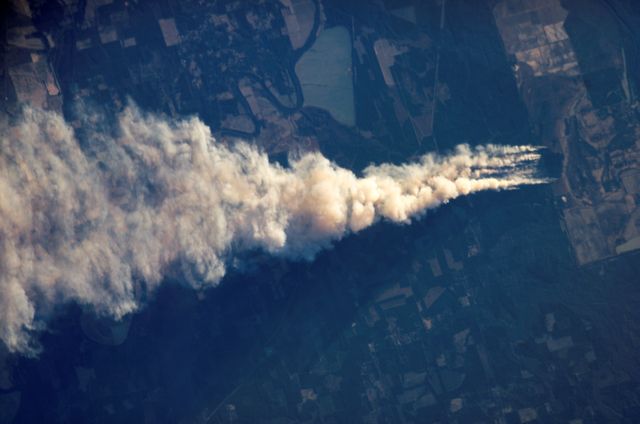 Smoke plume from a forest fire in Ouachita National Wildlife Refuge in Louisiana, viewed from International Space Station. Ideal for use in topics related to natural disasters, climate impact, environmental studies, and satellite imagery. Useful in educational materials on wildfires, ecosystem effects, and aerial phenomena. Can serve as a visual aid in news articles, presentations, and documentaries about wildfire management and environmental health.