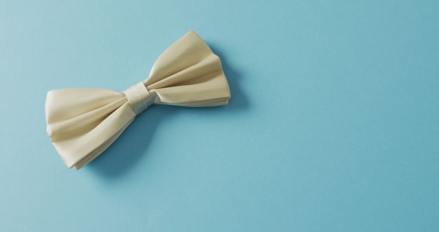 White bow tie placed on a blue background, ideal for fashion industry promotions, men’s clothing advertisements, and formal wear catalogues. Works well for representing style, sophistication, and luxury, suitable for event invitations and wedding-themed designs.