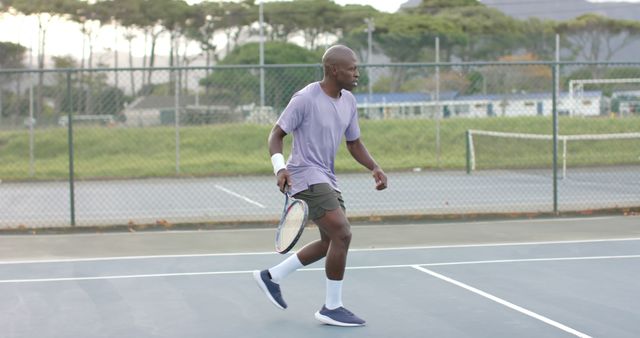 Young athletic man actively participating in a tennis match on an outdoor court on a summer day. Perfect for articles and advertisements relating to sports, fitness, healthy living, and active lifestyles. Suitable for use in promotional materials for health clubs, sports equipment, or athletic clothing brands.