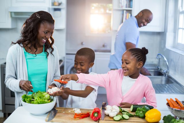 Family enjoying time together in kitchen, preparing a healthy meal with fresh vegetables. Ideal for promoting family bonding, healthy eating habits, and home lifestyle. Suitable for use in advertisements, blogs, and articles related to family activities, cooking, and nutrition.