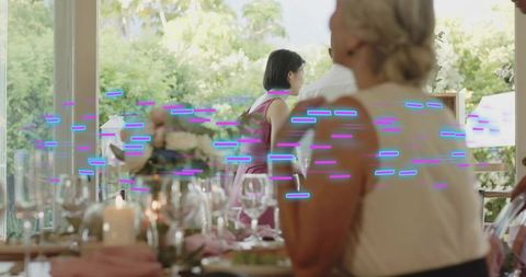 Senior woman turning at sunlit dining table during multigenerational garden gathering