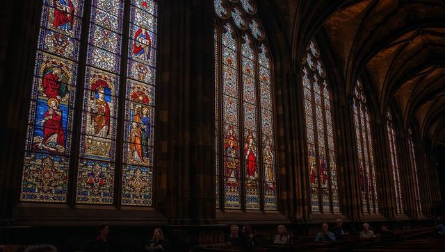 Tourists admiring stained glass windows in gothic cathedral