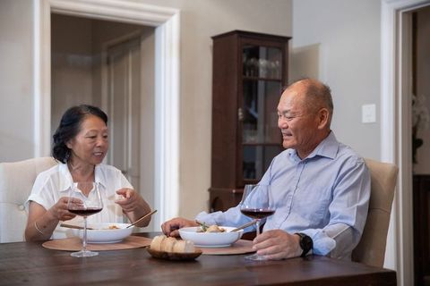 Senior asian couple sharing cozy dinner and red wine at home