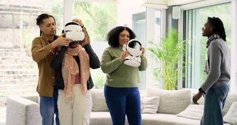 Multiracial friends testing virtual reality headsets in sunlit modern living room