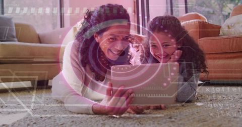Mother and daughter using tablet on rug with futuristic HUD overlay, smiling in cozy home
