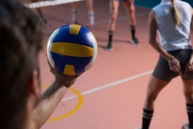  Cropped hand of player holding volleyball by female teammate at court