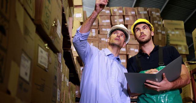 Warehouse Workers Discussing Inventory Management Among Stacks of Boxes - Download Free Stock Images Pikwizard.com