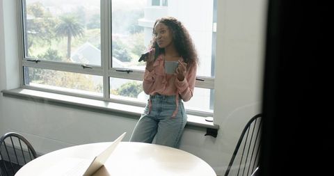 Young woman relaxed with microphone in sunlit office space