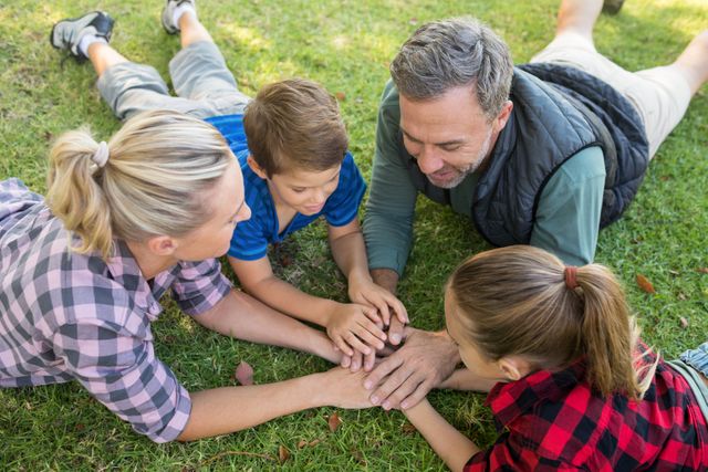 Playful family lying and putting their hands together in park