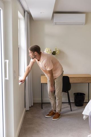 Contemplative young man at bedroom window finding tranquility
