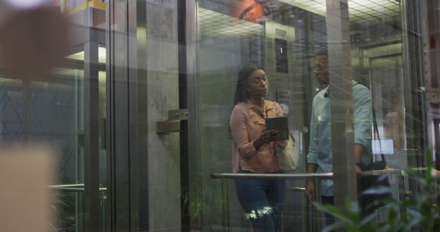 Image of diverse businesswoman and businessman talking in elevator. business professionals and working in office concept.