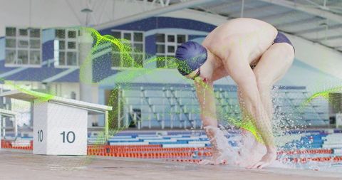 Competitive swimmer launching from starting block with green motion overlay and splash