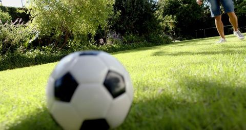 Young Man Playing with Soccer Ball on Sunny Lawn