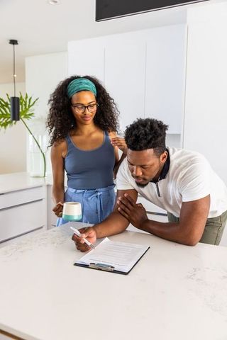 Couple reviewing paperwork on marble kitchen island, planning home finances and decisions