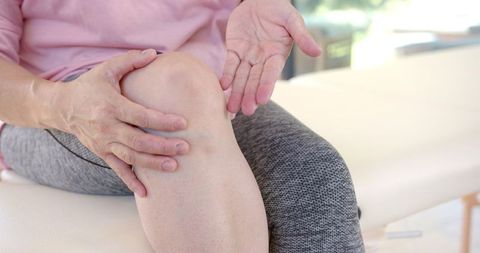 Senior asian woman experiencing knee pain in physiotherapy session
