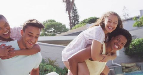 Smiling Friends Enjoying Piggyback Rides Outdoor