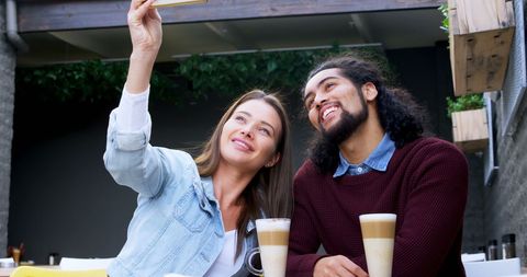 Happy Couple Taking Selfie at Outdoor Cafe with Drinks