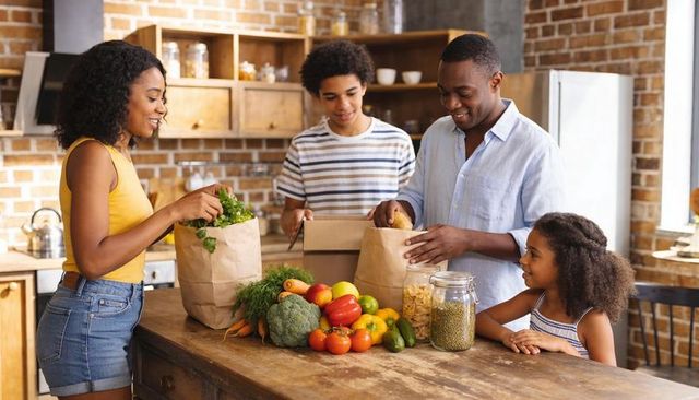 Happy family unpacking fresh groceries on rustic kitchen island with colorful produce and jars
