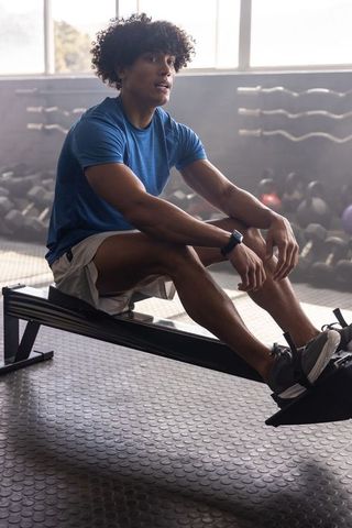 African american man resting on rowing machine after intense cardio workout in modern gym