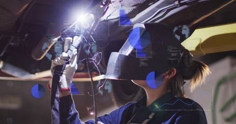 Female Auto Technician Welding Vehicle Undercarriage Using Torch and Protective Helmet