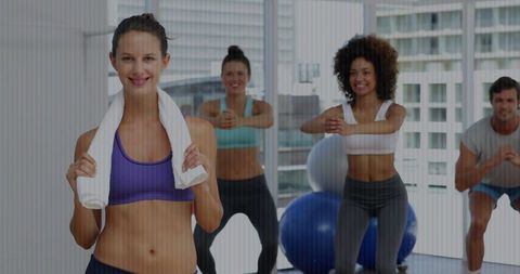 Fitness instructor leading energetic squat class in studio