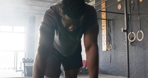 Focused Athlete in Industrial-Style Gym Leaning on Exercise Mat
