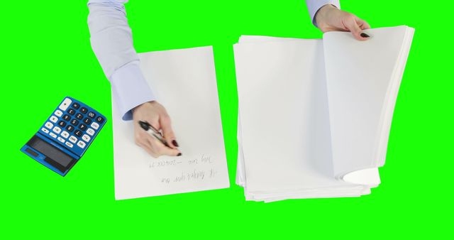 Person writing and managing large stack of papers with calculator nearby on green screen background. Useful for stock footage in business, finance, or education presentations requiring green screen for digital integration.