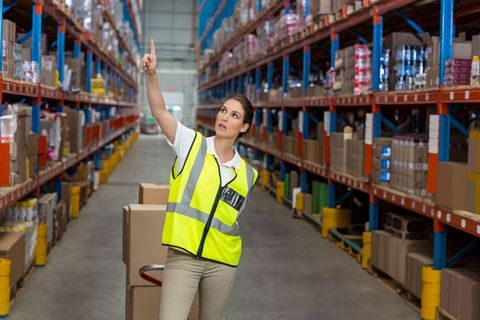 Female worker directing operations in large warehouse facility