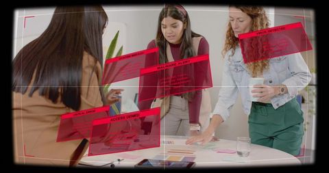 Creative team collaborating over mockups with augmented reality malware alerts overlay