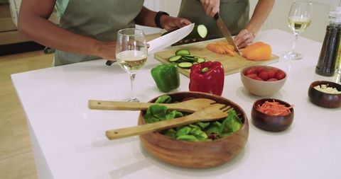 Women preparing fresh salad and vegetables in stylish kitchen