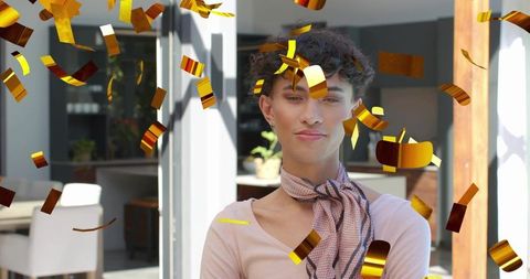 Sunlit backlit confetti celebration with androgynous male wearing scarf near sliding door