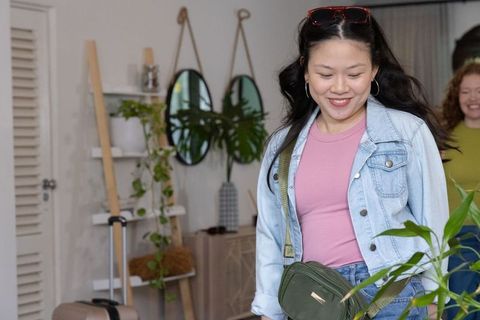 Asian woman walking in modern home decor showroom with friend carrying olive crossbody bag