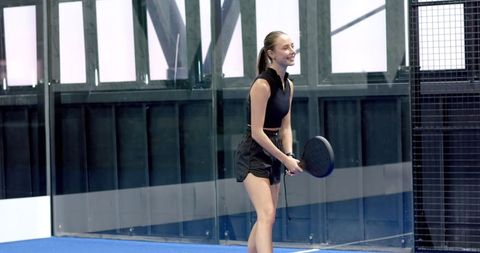 Female Athlete Holding Paddle Smiling in Modern Sport Environment