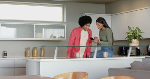 Interracial couple sharing smartphone in modern kitchen