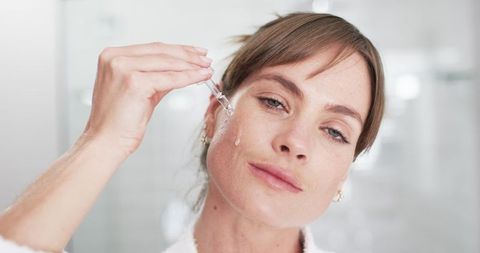 Middle-aged woman applying facial serum for self-care routine