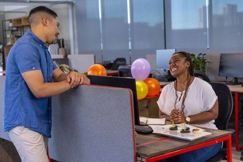 Diverse Coworkers Celebrating with Cupcakes and Balloons in Busy Office