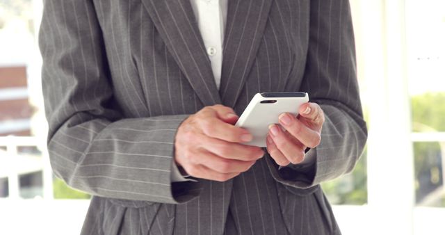 A middle-aged Caucasian businessman is using a smartphone, with copy space. His focus on the device suggests he might be checking emails, scheduling meetings, or staying connected on the go.