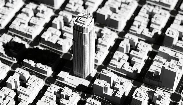 Monochrome aerial perspective showing highrise tower casting long shadow over grid