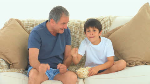 Grandfather and Grandson Enjoying TV with Popcorn