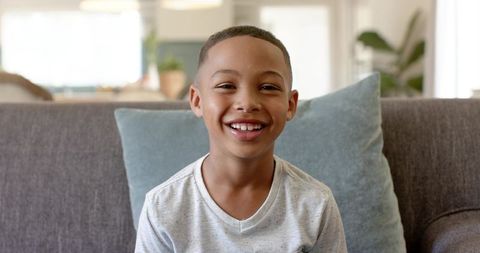 Smiling African American Boy Sitting on Sofa in Cozy Living Room