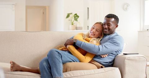 Happy interracial couple embracing on sofa relaxing together