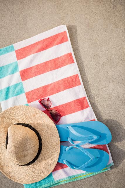 Straw hat, blue flip flop and sunglasses kept on beach blanket at beach