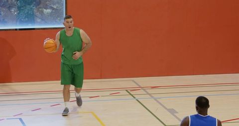 Dribbling guard driving fast break on indoor hardwood court with defender and copy space