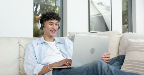 Young Man Enjoying Music While Using Laptop at Home